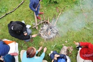 young people roasting food over a camp fire